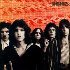 The cover of 'Sparks' by Sparks. A black and white picture of five very early 70s looking young men with curly hair, one with a small moustache, in front of a red brick wall.