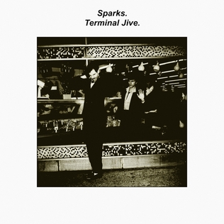 A black and white picture of three men in a shop. The man with the small moustache is in the foreground in front of a window, wearing a rather natty black suit. The other two appear to be behind the window.